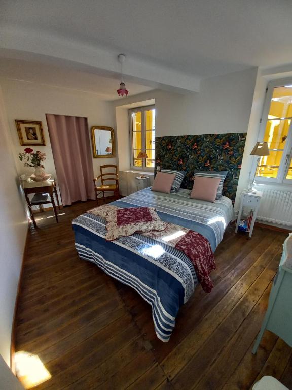 a bedroom with a large bed and wooden floors at Chambre Bleue - Ostau la Lutz in Saint-Germain-de-Calberte