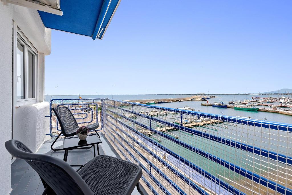 a balcony with two chairs and a view of a harbor at Vora Port in L'Ampolla