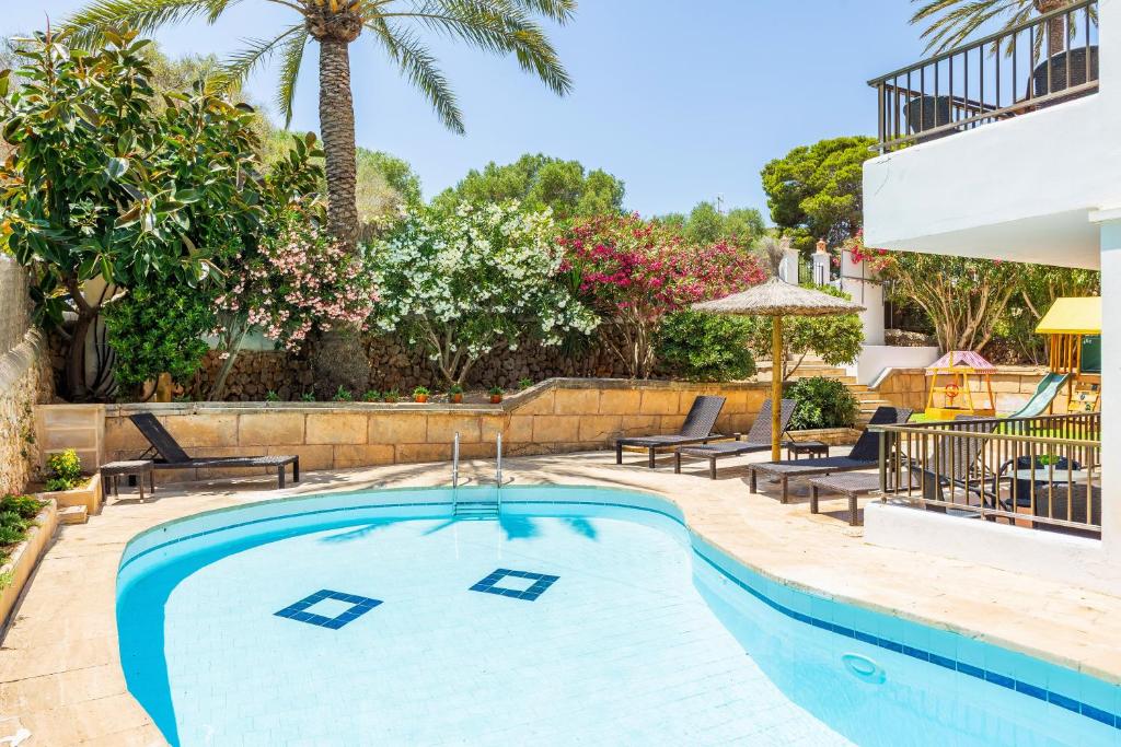 a swimming pool with chairs and a palm tree at Gran Sol Family 5 in Felanitx