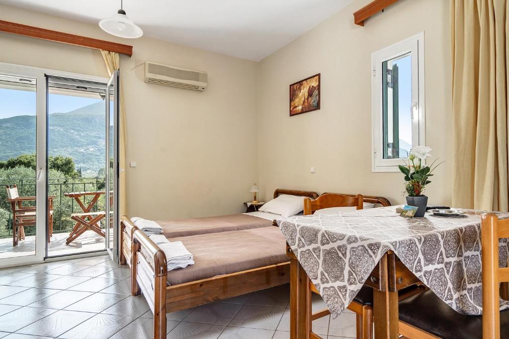 a bedroom with a bed and a table and a balcony at Daratos studio 1 in Kefallonia