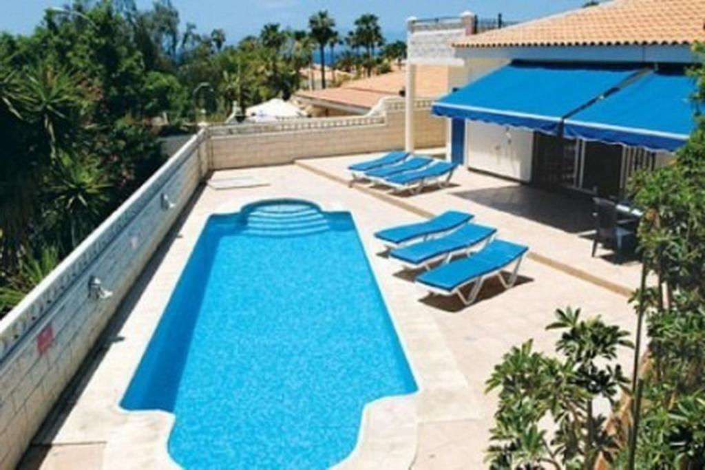 a swimming pool with blue chairs and a building at Salvaje Villa with private Pool in Adeje