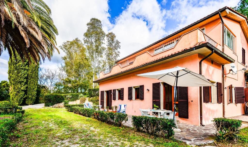 a pink house with a table and an umbrella at Villa Vanna Bilo A - bilocale in Capoliveri