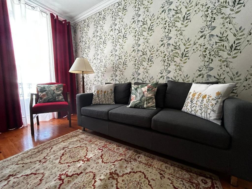 a living room with a black couch and a red chair at Desterro House in Angra do Heroísmo