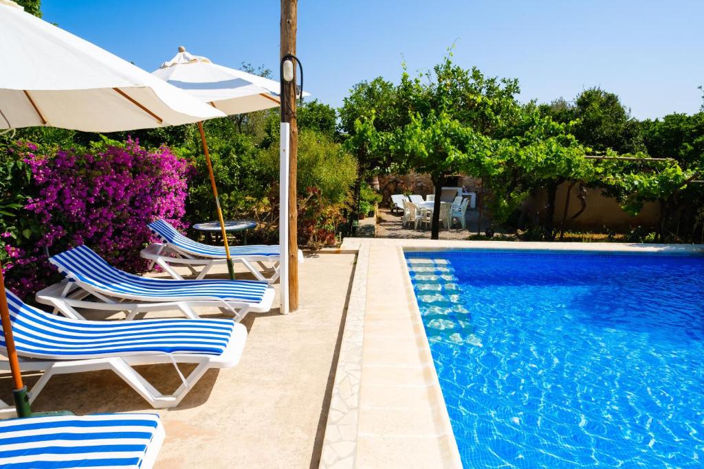 a group of chairs and an umbrella next to a swimming pool at Can Consul in San Juan Bautista