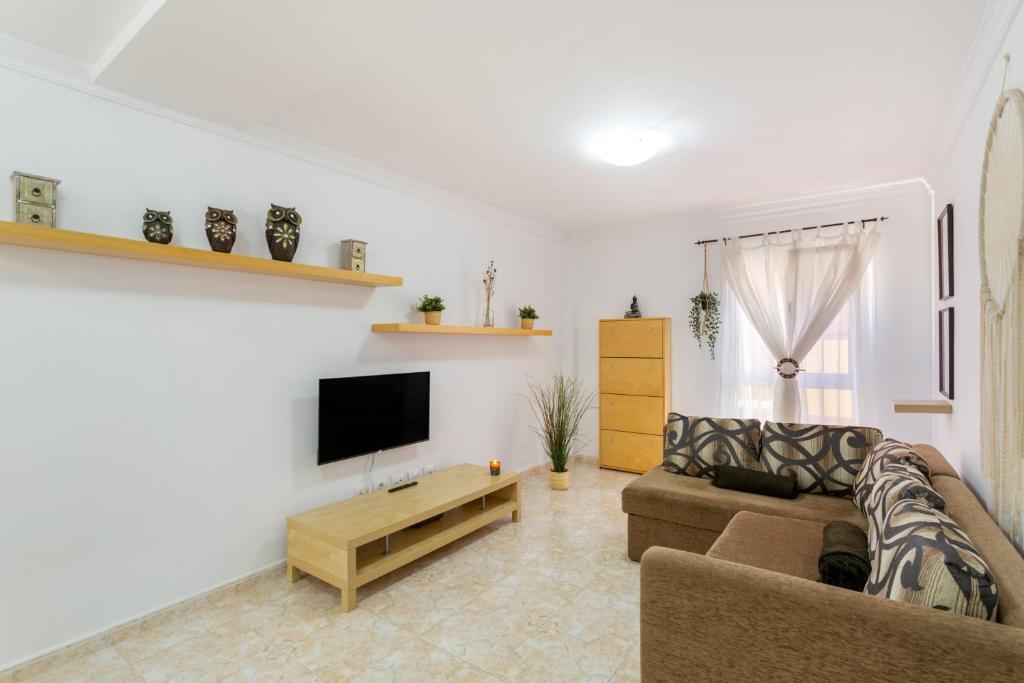 a living room with a couch and a tv at Attaday Home Holidays in Ingenio