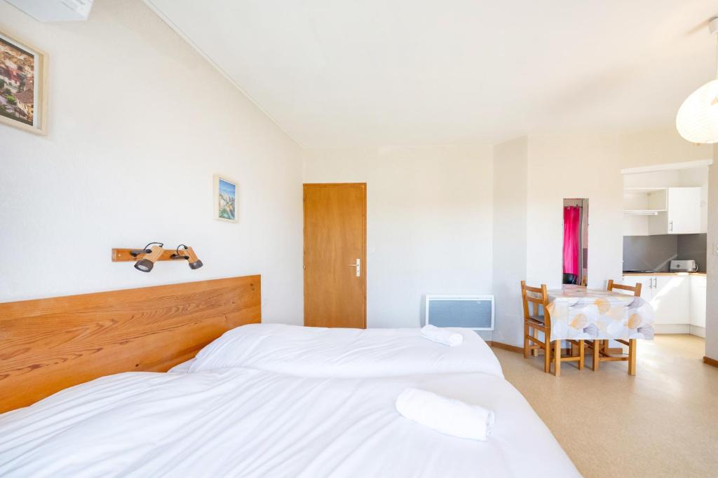 a bedroom with two white beds and a table at Les Mimosas - Appartement 08 in Cazaubon