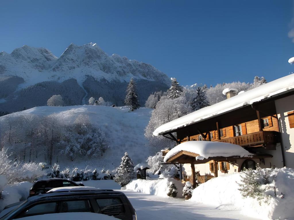 a building covered in snow with mountains in the background at Landhaus Reiser in Grainau