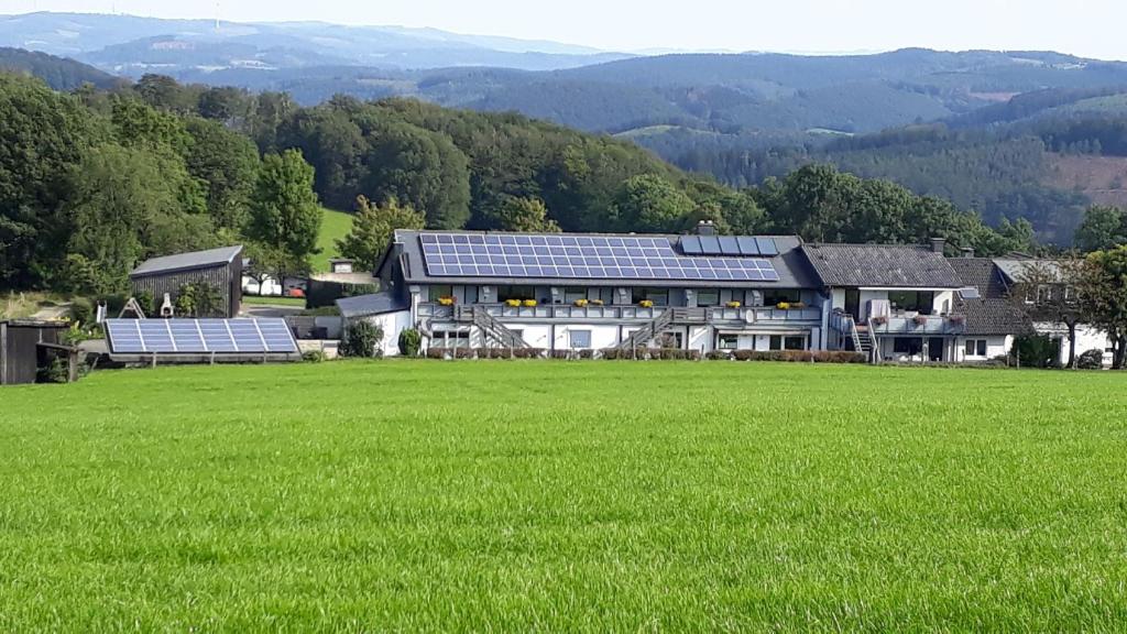 a large house with solar panels in a field at Ferienwohnungen Bußmann in Herscheid