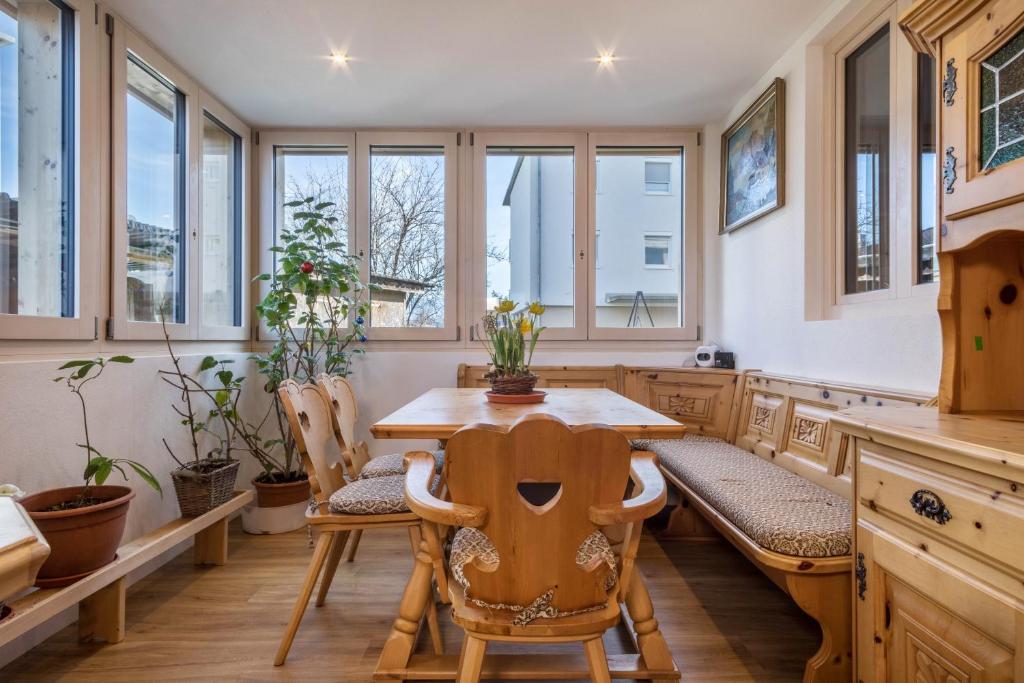 a kitchen with a wooden table and chairs and windows at Ferienwohnung Tannenblick in Höchst
