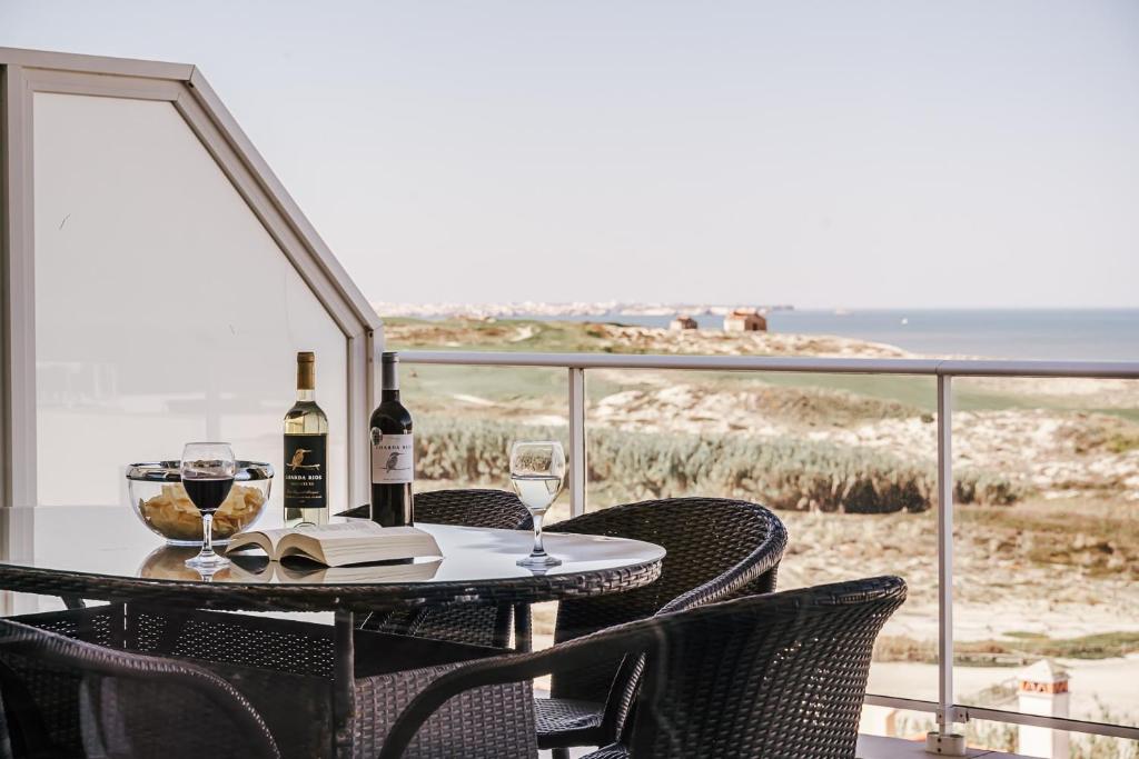 a table with two glasses of wine and a book at Beachfront Atlantic View A09 in Óbidos