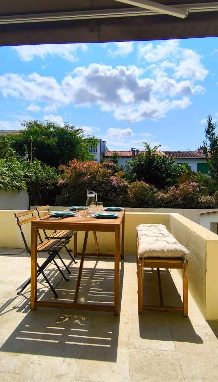 a wooden table and chair sitting on a patio at La douce Escale maison 2 chambres à 50 m de la plage in Royan