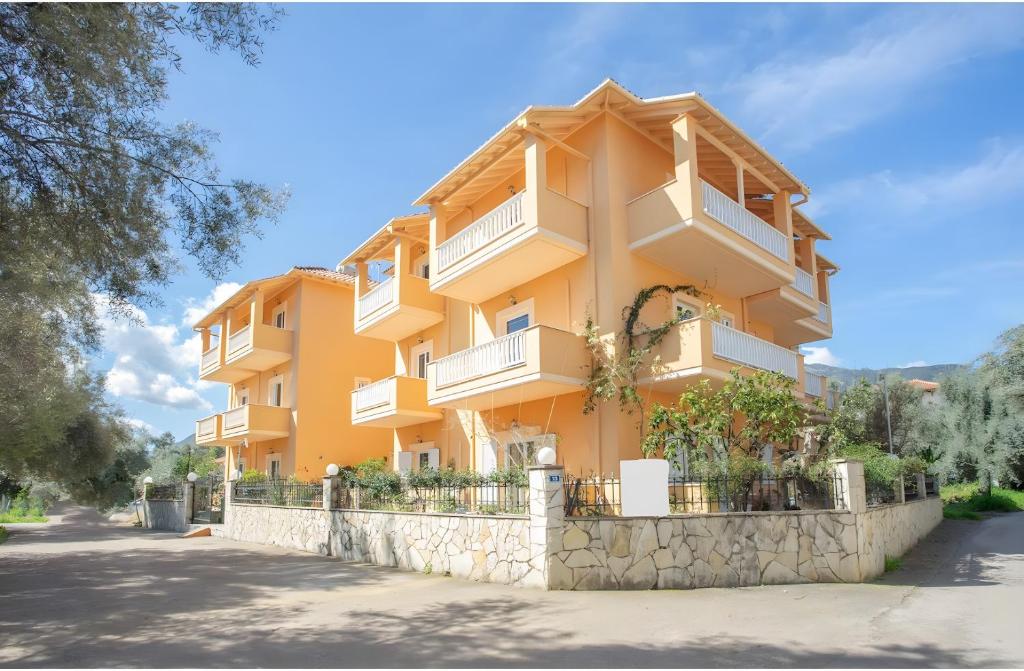 a yellow building with white balconies on a stone wall at Nidri view Apartments in Nydri