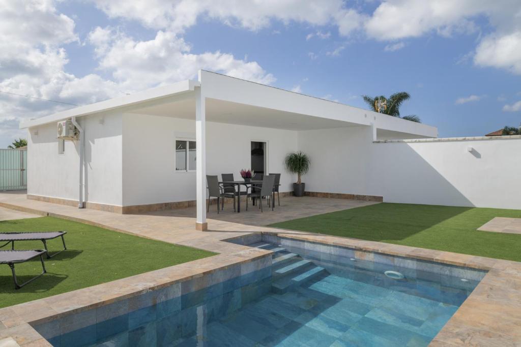 a white house with a swimming pool and a patio at Villa Laruma in Cádiz