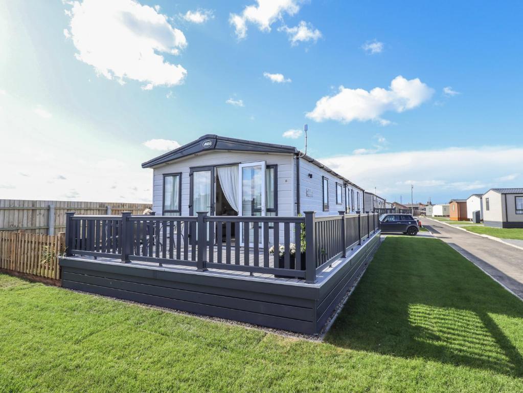 a modular house with a large deck on a lawn at Number 6 - Sandy Beach Holiday Park in Norwich