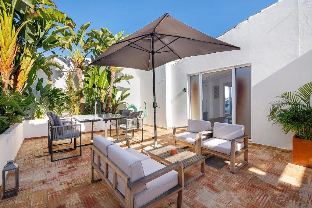 a patio with a table and chairs and an umbrella at Casa Papaya in Vila Nova De Cacela