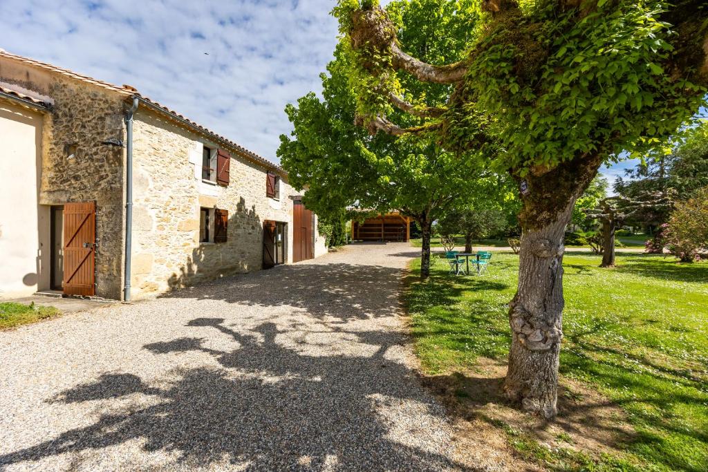 a tree in front of a building with a driveway at La Maison de Piquereau in Sauveterre-de-Guyenne