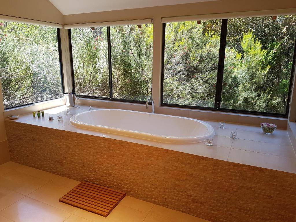 a large bath tub in a bathroom with windows at Jarrah Grove Forest Retreat in Rosa Glen