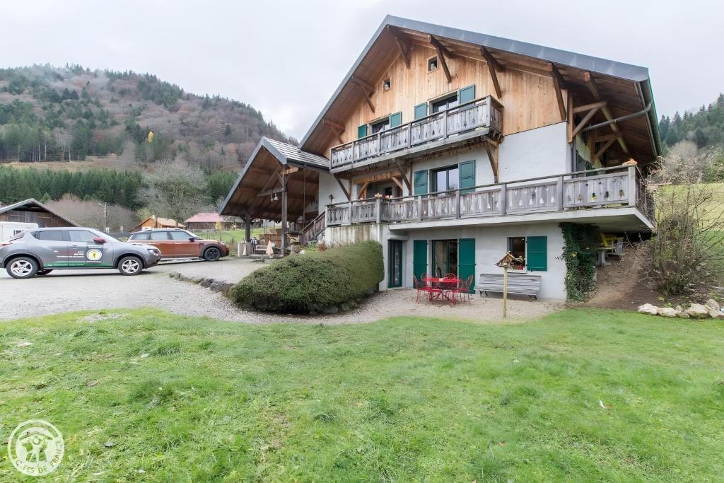 a large wooden house with cars parked in front of it at Gîte Chez Mayon in Orcier