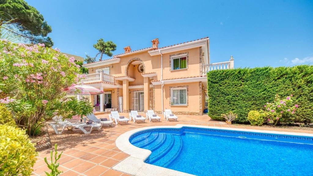 a villa with a swimming pool in front of a house at Costacabana - Villa Primavera in Lloret de Mar