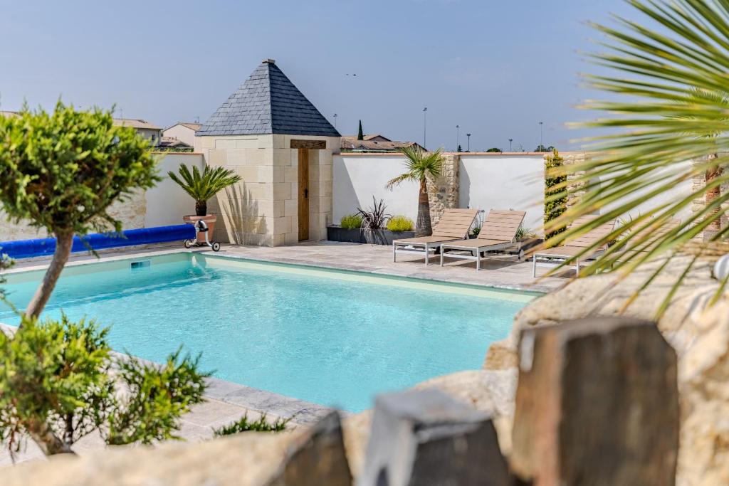 a swimming pool with two chaise lounges next to a house at Maison Les Marronniers in Montagne