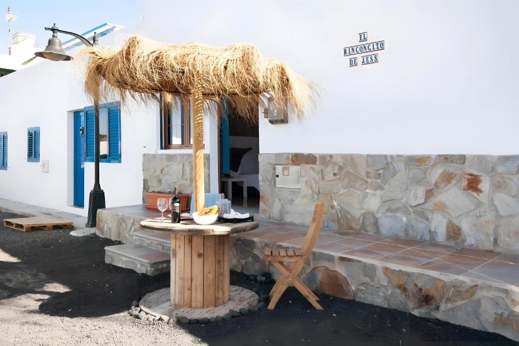 a table with a straw umbrella in front of a building at El rinconcito de Jess in El Golfo