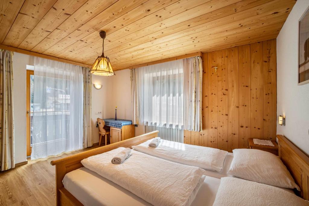 a bedroom with two beds in a room with wooden walls at Gartnerhof Apt Rose in Colle Isarco