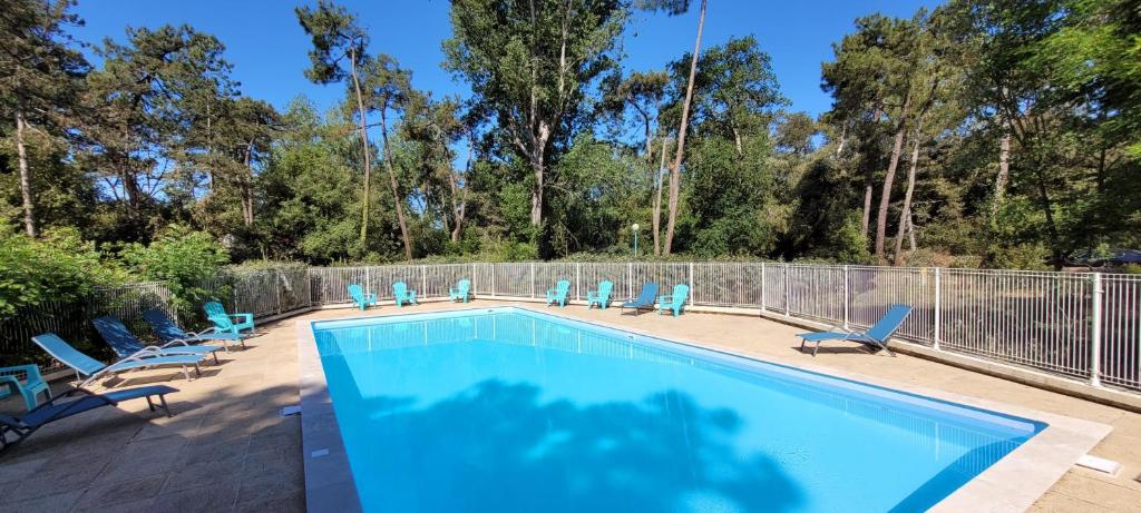 a swimming pool with blue chairs and a fence at Le studio d'Apoline avec piscine in La Tranche-sur-Mer