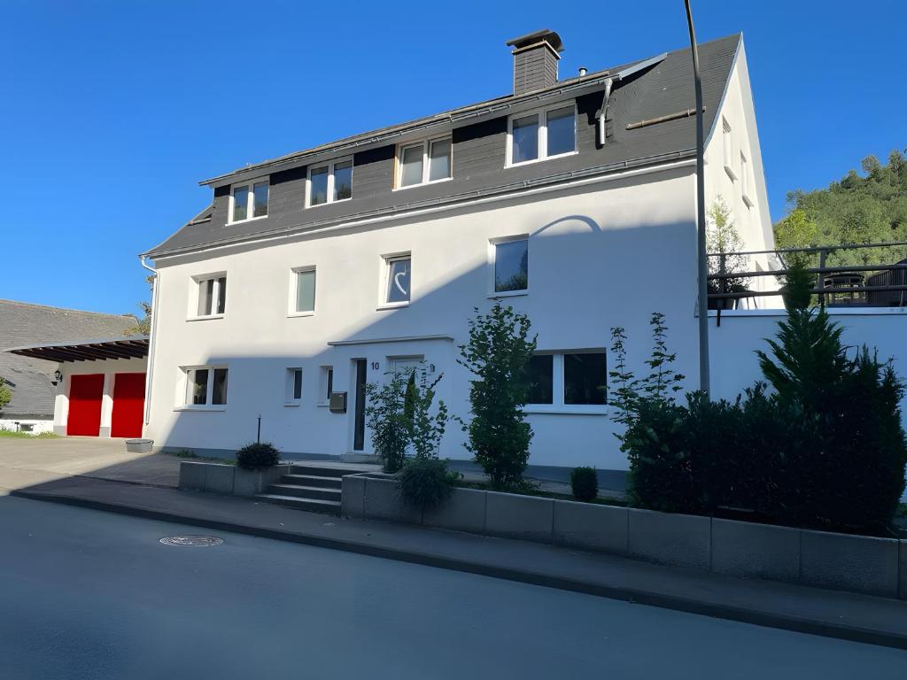 a white building with a lot of plants in front of it at Sauerland Apartments Willingen in Willingen