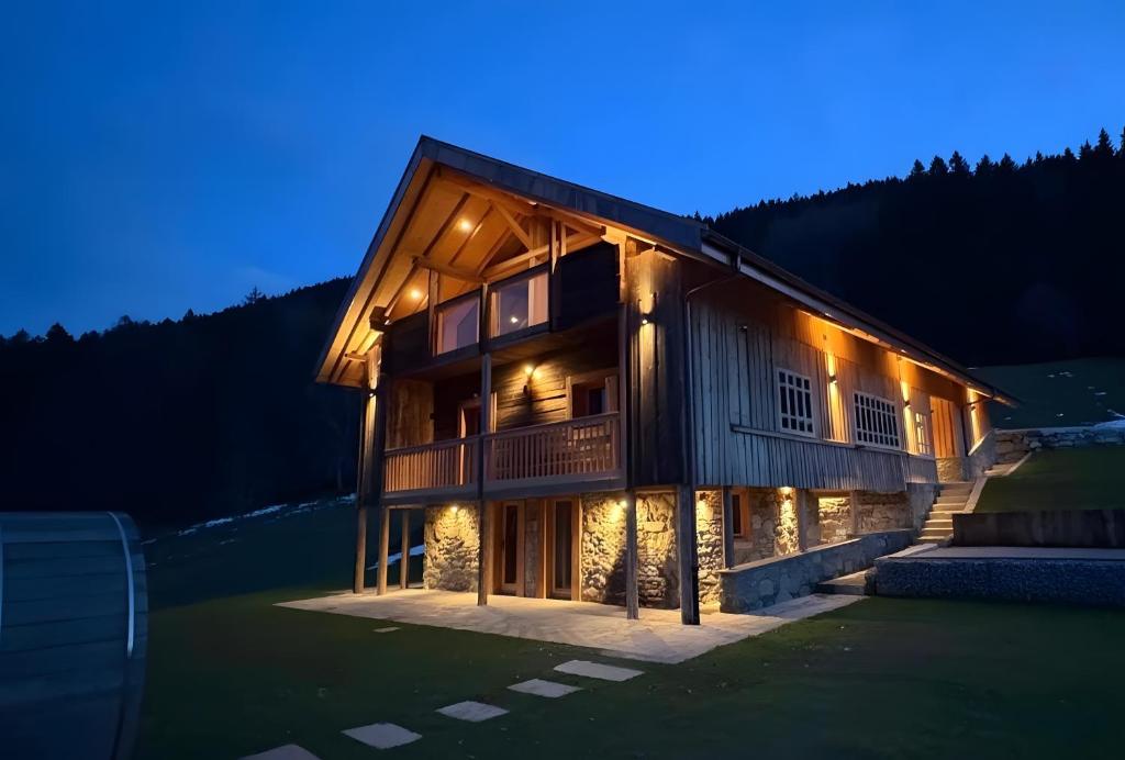 a large wooden house with lights on it at night at Lisalice appartement in Les Villards-sur-Thônes