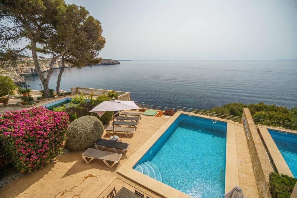 a pool with chairs and an umbrella next to the water at Mediterranean Vacation in Mallorca in Cala Pi