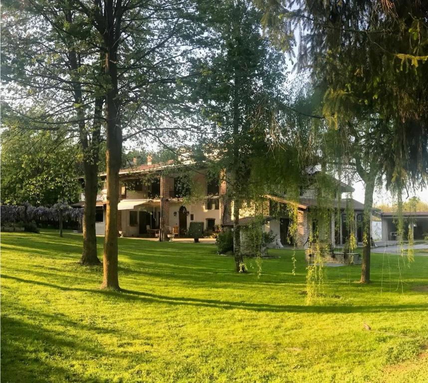 a house in a field with trees in the foreground at Alpi Liguri - Villa Giulia in Peveragno