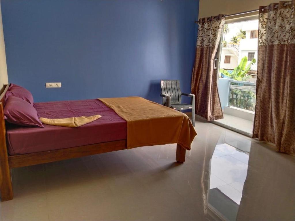 a bedroom with a bed with a blue wall and a window at CloudGuestHouse in Kottakupam