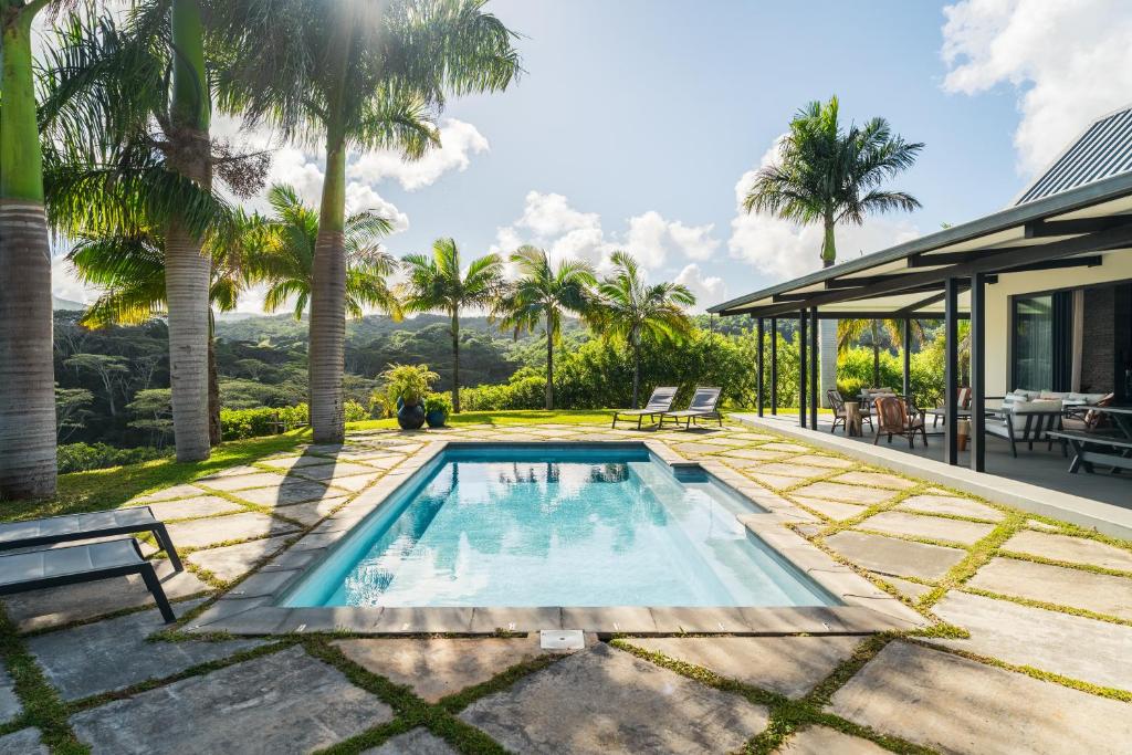 a swimming pool in the backyard of a house with palm trees at Villa Kamaya, Chamarel in Chamarel