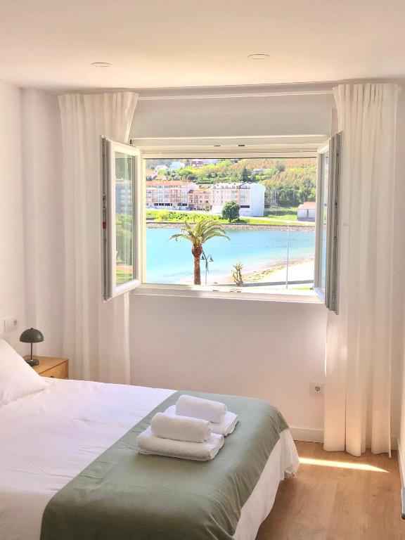 a bedroom with a window with towels on a bed at A Ribeira - BoaOnda in Cee