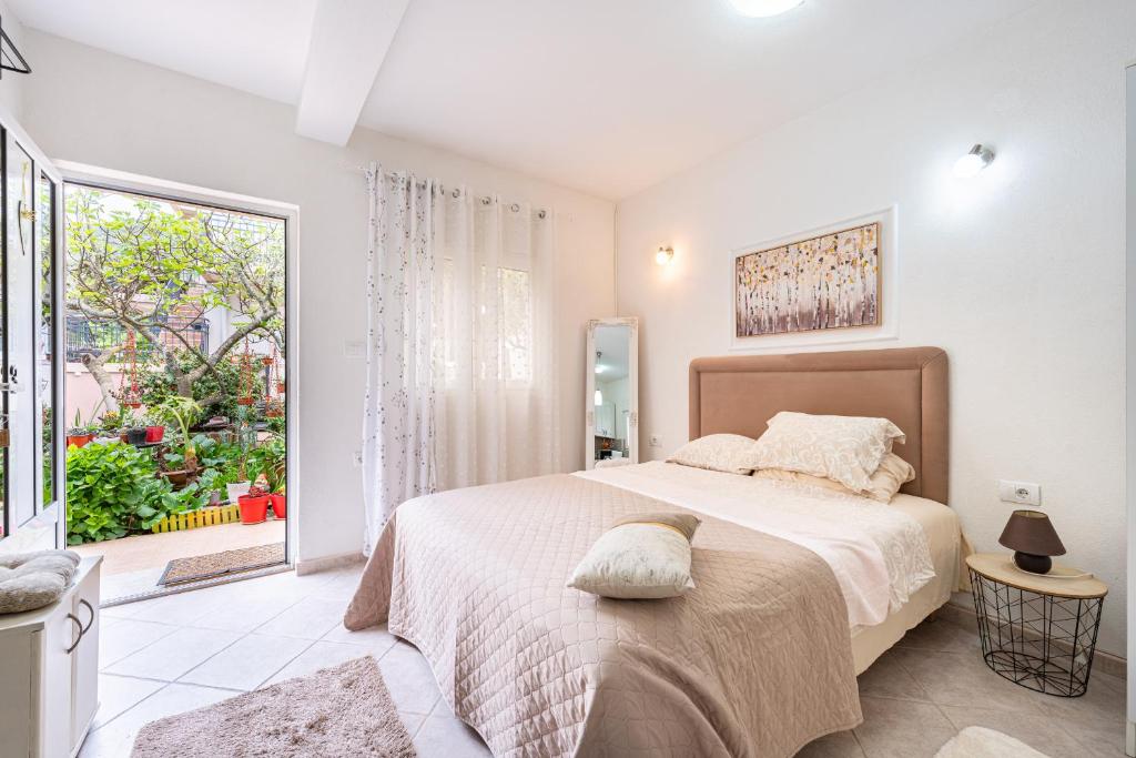 a white bedroom with a large bed and a window at Apartments Gabi&Zdenka Tivat in Tivat