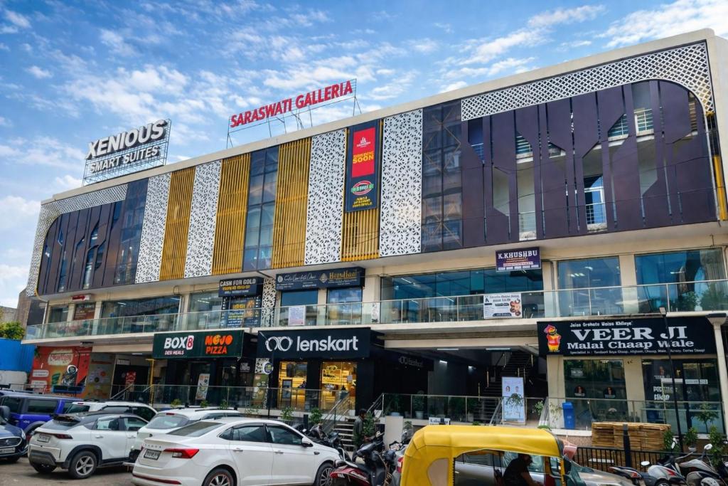 a large building with cars parked in a parking lot at Xenious Smart Suites Greater Noida in Noida