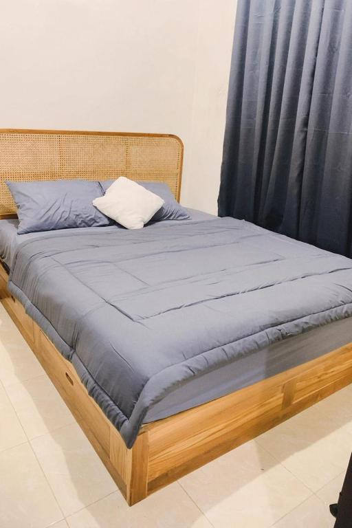 a bed with a wooden frame with a blue blanket at SS house in Tabanan