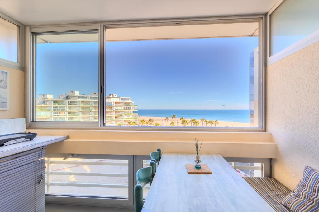 a room with a large window with a view of the beach at Studio vue mer in Canet-en-Roussillon