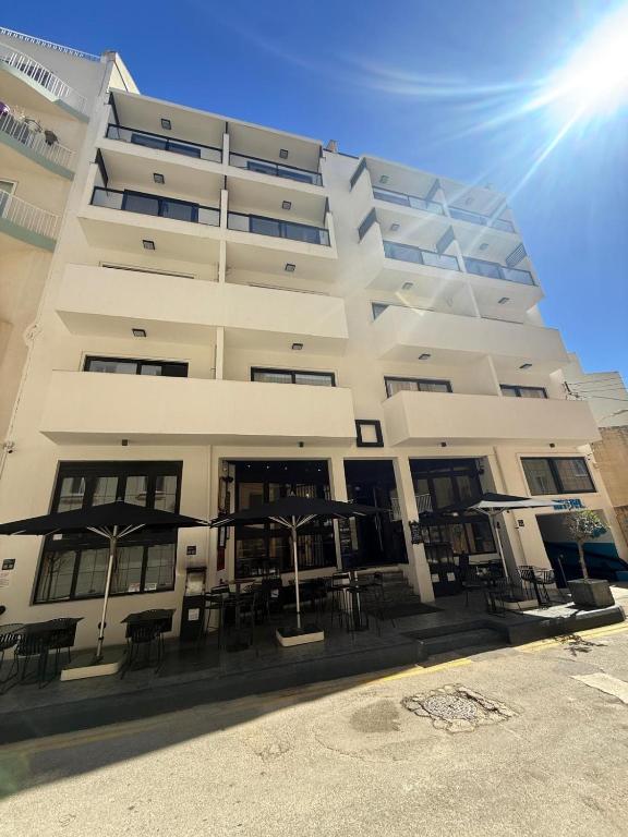 a white building with tables and chairs in front of it at Block in Xlendi