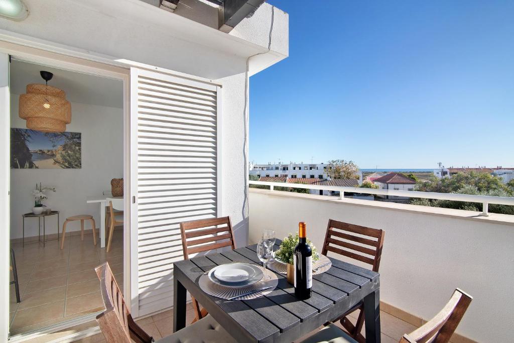 a dining room with a table and chairs and a balcony at Tavira Mar in Cabanas de Tavira
