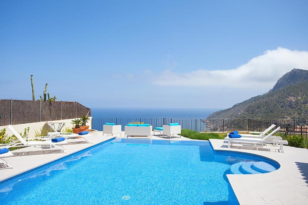 a pool with chairs and a view of the ocean at Villa Mar y Muntana in Banyalbufar