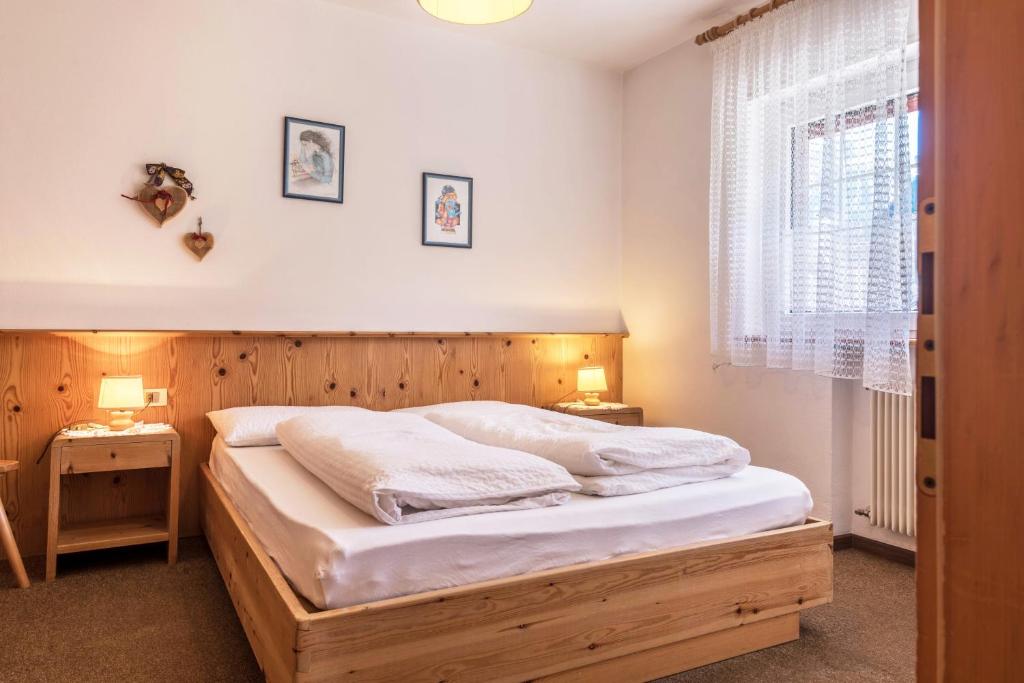a bedroom with a wooden bed and a window at Casa Lorenz 1 in Canazei
