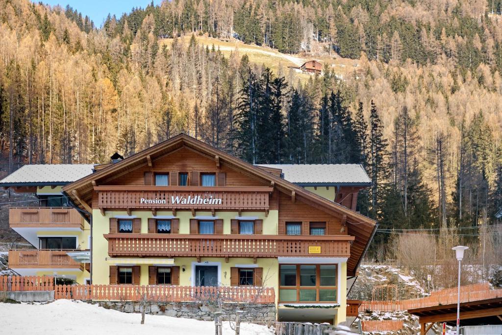 a large building in the snow with a mountain at Pension Waldheim Apartments in San Giacomo