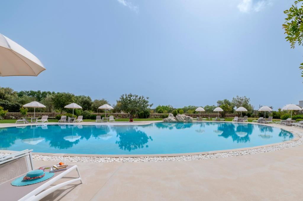 a large swimming pool with chairs and umbrellas at Tenuta Vigna Corallo - Mimosa in Otranto
