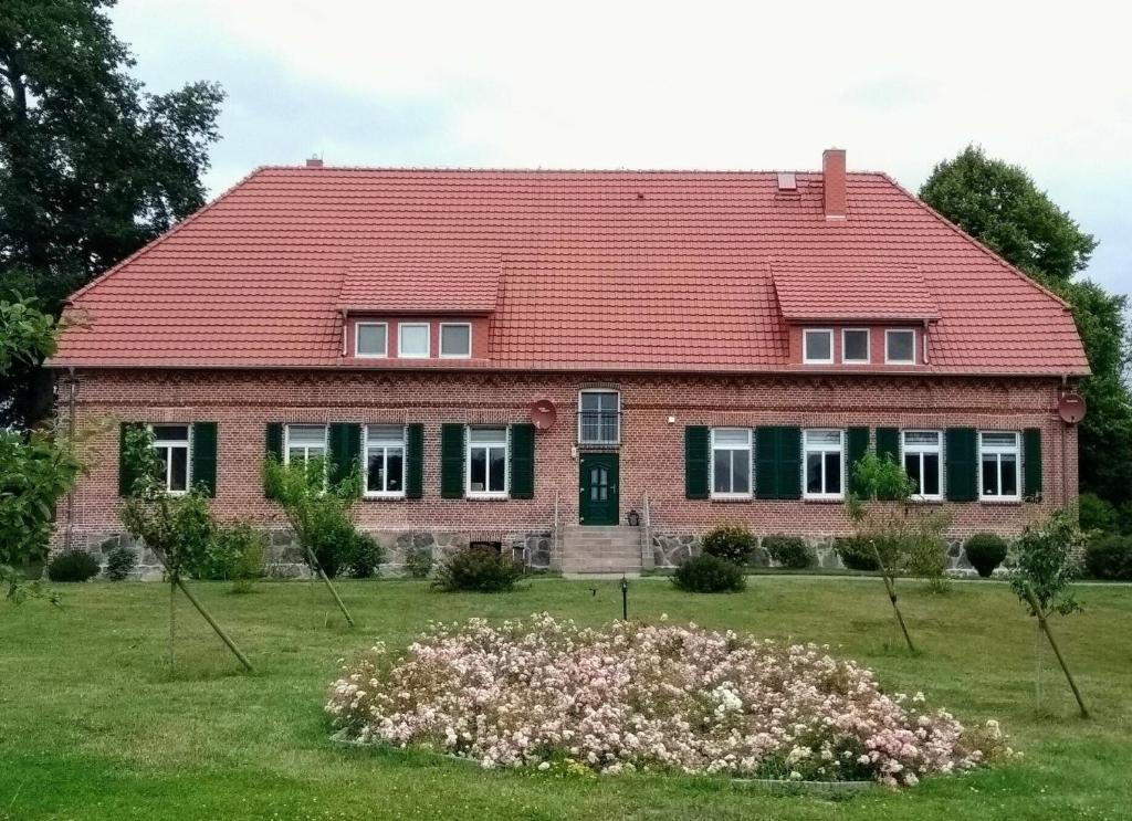 a house with a red roof and a field of flowers at Das Landhaus Wohnung 1 in Kirch Mulsow
