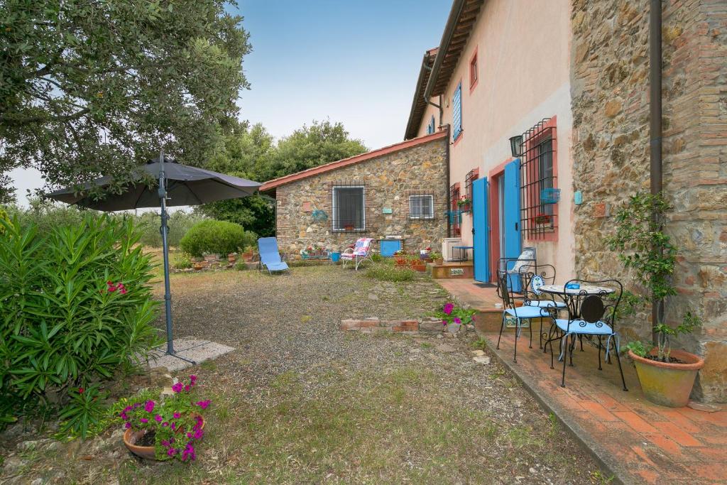 a patio with chairs and an umbrella next to a building at Casa Pel di Lupo in Rosignano Marittimo