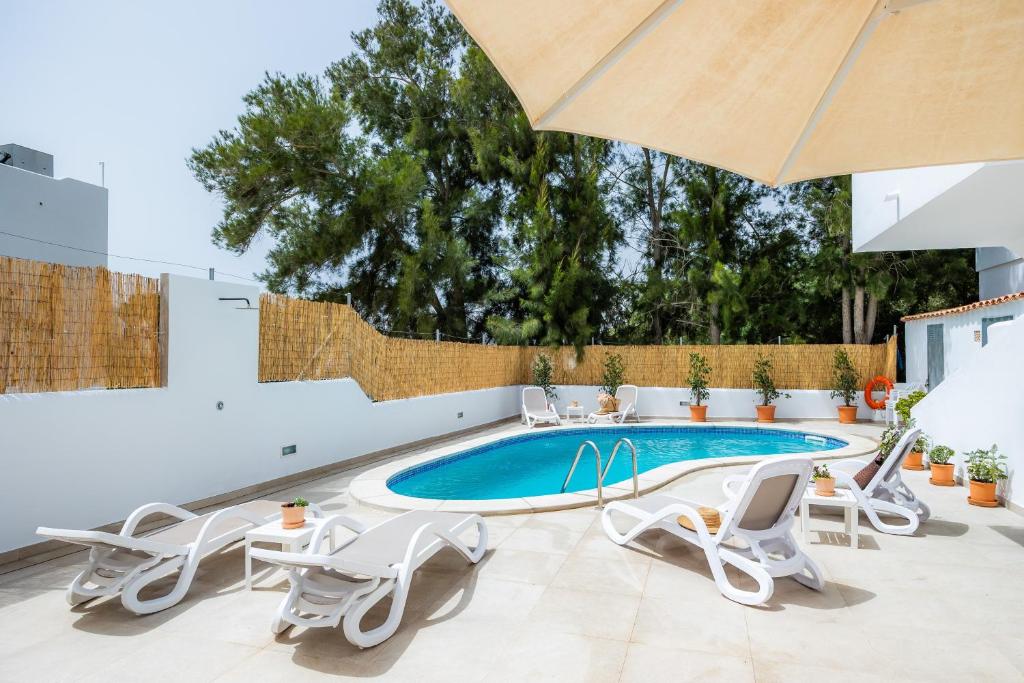 a swimming pool with chairs and an umbrella at White suites 3 in Cala d´Or