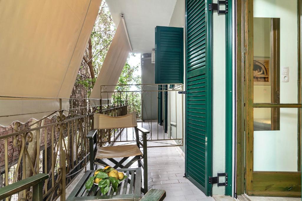 a balcony with green shutters and a table and chairs at Old Boat double studio 2 in Nikiana