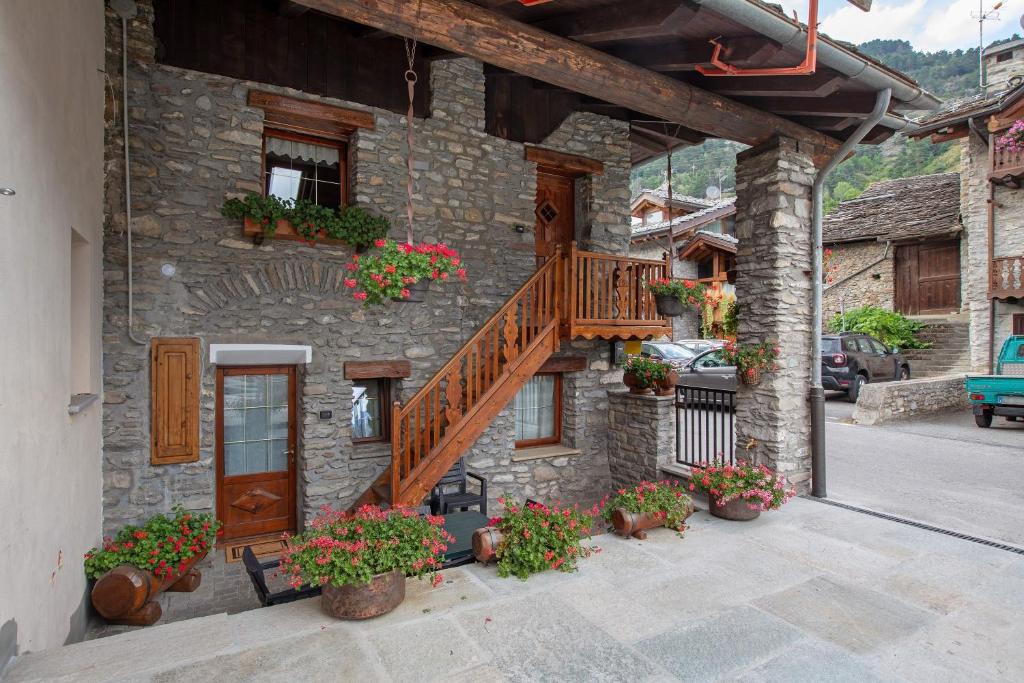 a stone building with a staircase and flowers on it at Casa Piertor Morgex in Morgex