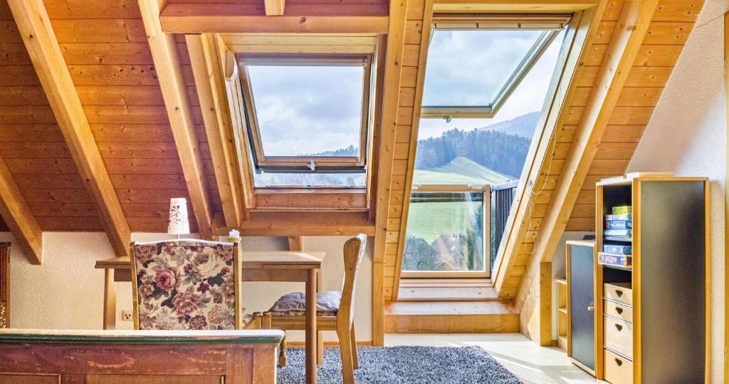a room with two windows and a table and a chair at Ferienwohnung Pfisterhof in Kirchzarten
